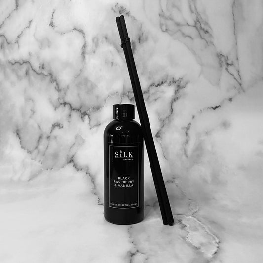 A black plastic bottle with a bundle of black diffuser reeds