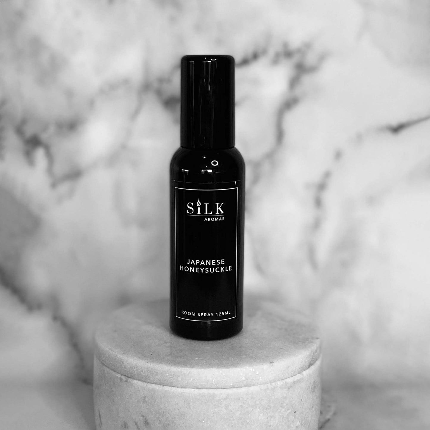 A black plastic room spray bottle with a black lid and black label