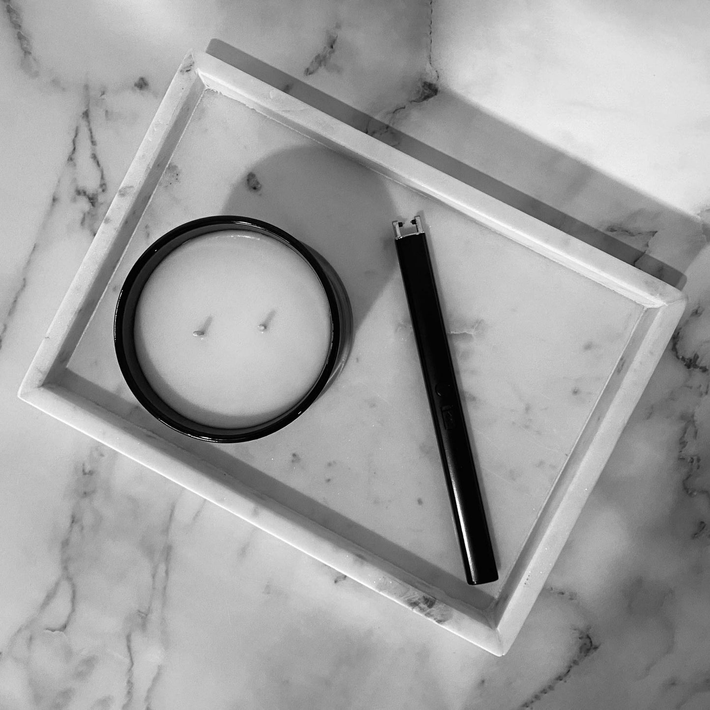 A sleek, black electric candle lighter on a white marble tray