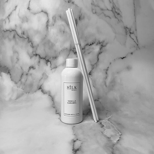 A white plastic bottle with a bundle of white diffuser reeds