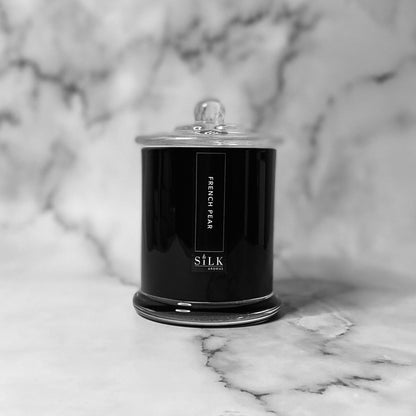 A black glossy candle jar with clear glass apothecary lid